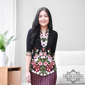 Peut inclure: Haut noir brodé avec un motif floral et paon. Le haut présente un décolleté en V et des manches trois-quarts. La broderie comprend des fleurs roses, rouges et blanches avec des feuilles vertes. Le bas est une jupe plissée.