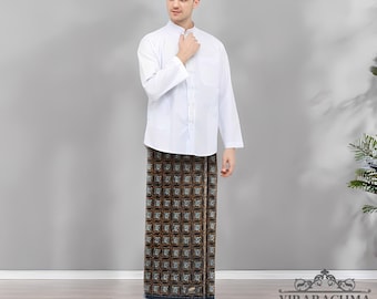 May include: A man wearing a white long-sleeved shirt, a patterned sarong, black sandals, and a black cap. The sarong features a repeating geometric design in shades of brown, black, and blue. The outfit is a traditional style.