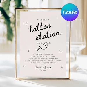 May include: A framed sign with the words "tattoo station" in a handwritten font, with a heart and arrow graphic. The sign includes instructions for applying temporary tattoos and the names Darcy & James, with the date 11.11.25.