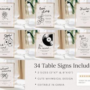 May include: A collection of framed table signs with gold frames, featuring black and white illustrations and text. The signs include phrases like "In Loving Memory," "Our Love Story," and "Freshen Up." The image also includes text stating "34 Table Signs Included."