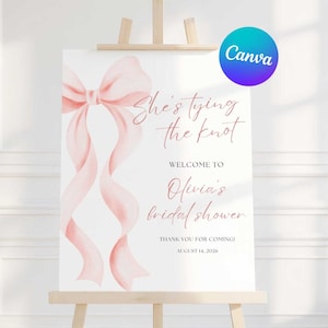 May include: A white sign on an easel with a pink bow and ribbons design. The sign reads "She's tying the knot" and welcomes guests to Olivia's bridal shower, dated August 14, 2026. The Canva logo is in the upper right corner.