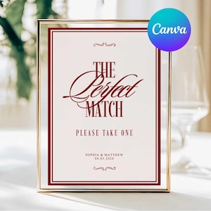 May include: A framed sign with the text "The Perfect Match" in burgundy script. The sign includes the names Sophia & Matthew and the date 04.05.2026. The sign is in a gold frame and is likely for a wedding or engagement.