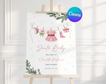 May include: A baby shower sign on an easel with a watercolor design. The sign reads "Santa Baby" and welcomes guests to Charlotte Walker's baby shower. The design includes a clothesline with baby clothes and Christmas decorations.