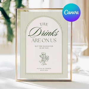 May include: A framed sign with the text "THE Drinks ARE ON US" in elegant script, with the words "BUT THE HANGOVER IS ON YOU" below. The sign includes a drawing of cocktail glasses and the names Olivia & Conrad with a date. A Canva logo is in the top right corner.