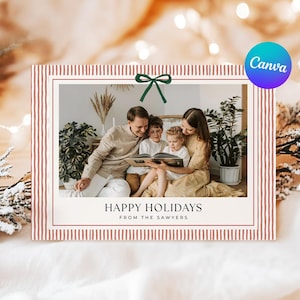 May include: Holiday card with a family reading a book. The card has a red and white striped border and a green bow. The text reads "Happy Holidays From The Sawyers."