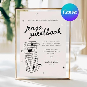 Puede incluir: Un letrero enmarcado con las palabras "jenga guestbook" en una fuente decorativa. El letrero incluye una ilustración de la torre Jenga y texto que invita a los invitados a firmar una pieza de Jenga con buenos deseos para los recién casados. El letrero está en un marco dorado.