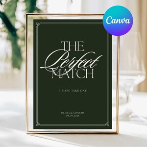 Puede incluir: Un letrero enmarcado con el texto "THE Perfect MATCH" en elegante escritura blanca sobre un fondo verde oscuro. El letrero también incluye el texto "PLEASE TAKE ONE" y nombres y una fecha. El marco es dorado.