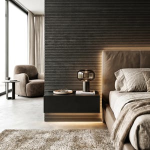 May include: A floating black rectangular nightstand mounted against a dark horizontal slatted wall. A modern table lamp with a dark glass shade sits on the surface next to a small white tray containing eyeglasses and a book, illuminated by warm light.