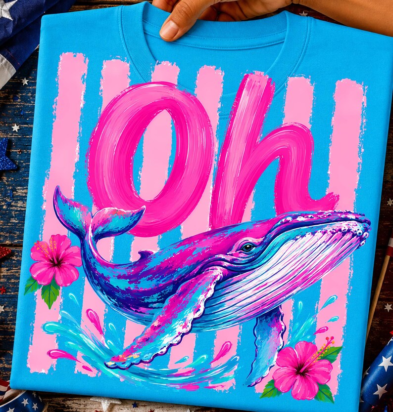 Pu&ograve; includere: Una t-shirt blu brillante con una grande scritta rosa a pennellate che recita "Oh" sopra un'illustrazione colorata di una balena. Il design include strisce verticali rosa, due vivaci fiori di ibisco rosa e spruzzi d'acqua blu.