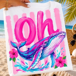 Pu&ograve; includere: Una t-shirt bianca con una grande scritta rosa a pennellate che recita Oh, una vivace grafica di una balena blu e viola e due fiori di ibisco rosa brillante. Il design include strisce verticali rosa e spruzzi d'acqua blu.