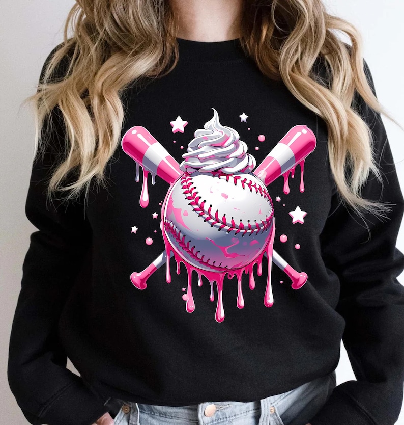 May include: Black sweatshirt with a baseball-themed design. The baseball has pink dripping details, crossed pink and white striped bats, and a swirl of whipped cream. White stars are scattered around the design, creating a playful aesthetic.