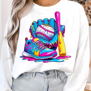 May include: A white sweatshirt with a baseball-themed illustration. The design features a baseball, glove, bat, and a trainer, in bright blue, pink, and yellow. The baseball is decorated with colourful sprinkles.