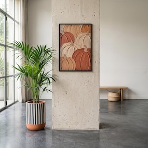 May include: A rectangular wall art piece featuring a textured, impasto-style painting of multiple pumpkins in shades of terracotta, beige, and cream, enclosed in a thin black frame and mounted on a concrete pillar next to a striped planter.