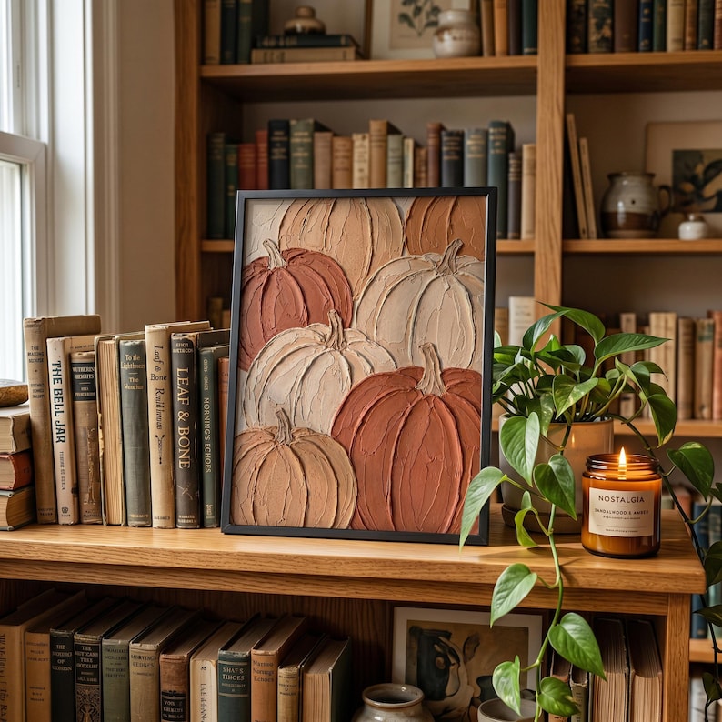 May include: A framed wall art piece featuring a textured impasto painting of multiple pumpkins in shades of cream, beige, tan, and burnt orange. The artwork is displayed in a thin black frame, showcasing thick, raised paint strokes throughout.