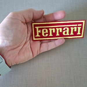 Puede incluir: Una taza de cerámica blanca con un asa negra y el texto "But First, Coffee" en un estilo manuscrito. La taza está sobre una superficie blanca. La taza mide aproximadamente 10 cm de alto.