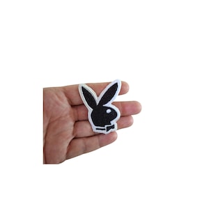 May include: A black and white embroidered patch featuring the iconic rabbit head logo. The patch has a black rabbit silhouette with a white outline. The patch is held in a hand against a white background.