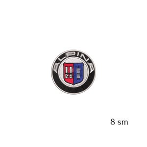 May include: Embroidered patch featuring the word "ALPINA" in a circular design. The patch has a black border and a shield emblem with red and blue sections. The patch is approximately 3 inches in diameter.