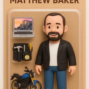 Op de afbeelding: Een Mattel actiefiguur van Matthew Baker, verpakt op een kartonnen achtergrond. De figuur draagt een zwarte blazer, een wit shirt en een blauwe jeans. Accessoires zijn een laptop, een gereedschapsset en een blauw-gele motorfiets. De verpakking leest "MATTHEW BAKER".