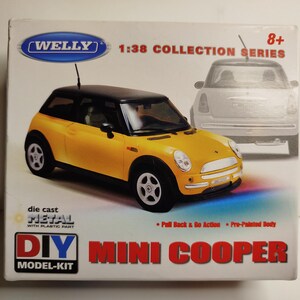 以下が含まれることがあります： 箱に入った黄色と黒のミニクーパーの模型。箱には「DIY MINI COOPER MODEL-KIT」と「1:38 COLLECTION SERIES」と書かれています。この車は、ダイキャストメタルとプラスチックパーツでできています。