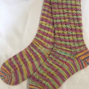 May include: A pair of colorful striped socks with a yellow, pink, green, and purple color scheme. The socks are made of a soft, knitted fabric.