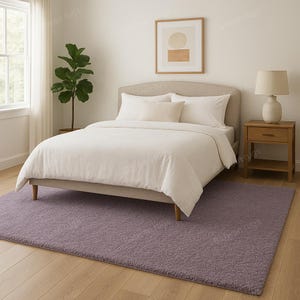 May include: A bedroom scene featuring a bed with white bedding, a nightstand with a lamp, and a large, rectangular, purple rug. A potted plant and artwork are also visible. The room has a neutral color palette, creating a calming atmosphere.