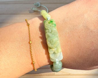 May include: A green jade bracelet with a carved floral design. The bracelet is made of jade beads and has a string closure.