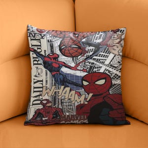 Puede incluir: Cojín cuadrado con un diseño de cómic con ilustraciones de Spider-Man. El cojín tiene un fondo blanco con paisajes urbanos en blanco y negro y texto de cómic, incluyendo "WHAAAM!" y "MARVEL COMICS".