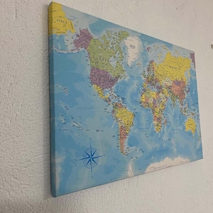 May include: A blue world map printed on canvas with country borders and names. The map includes a compass rose and the words "Pacific Ocean" and "Antarctica".