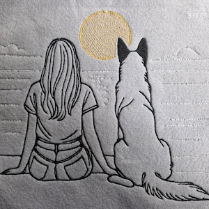 Può includere: Un disegno in bianco e nero di una persona e un cane seduti uno accanto all'altro, che guardano un sole giallo in lontananza. L'immagine è ricamata su un tessuto grigio.