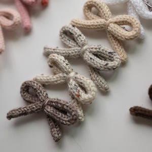 Pode incluir: Um conjunto de nove la&ccedil;os de cabelo de malha em v&aacute;rios tons de marrom, bege e branco. Os la&ccedil;os s&atilde;o feitos com um fio macio e texturizado e t&ecirc;m um design simples e elegante.