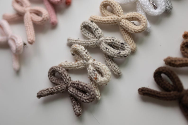 Pode incluir: Um conjunto de nove la&ccedil;os de cabelo de malha em v&aacute;rios tons de marrom, bege e branco. Os la&ccedil;os s&atilde;o feitos com um fio macio e texturizado e t&ecirc;m um design simples e elegante.