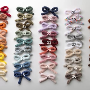 Pode incluir: Quarenta e um la&ccedil;os de malha feitos &agrave; m&atilde;o em v&aacute;rias cores, incluindo vermelho, verde, azul, rosa, marrom e branco. Os la&ccedil;os est&atilde;o dispostos em filas, numeradas de 1 a 41.
