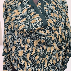 May include: A green and tan patterned scarf with a swirling design. The scarf is made of a soft, lightweight fabric and is perfect for adding a touch of style to any outfit.