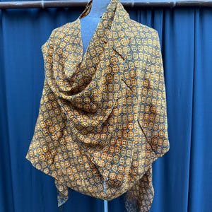 Peut inclure: Une écharpe à motifs jaunes et noirs avec un design géométrique. L'écharpe est drapé sur un mannequin.