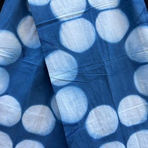 Op de afbeelding: Een blauwe stof met witte stippen. De stof is dubbelgevouwen, waardoor het patroon aan beide kanten zichtbaar is.