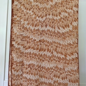 May include: A brown silk scarf with a white leaf pattern. The leaves are arranged in a repeating pattern that creates a sense of movement.