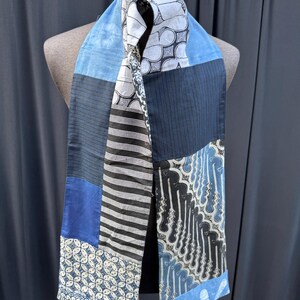 Peut inclure: Une écharpe en patchwork bleu et blanc avec différents motifs, notamment des rayures, des motifs géométriques et des motifs floraux.