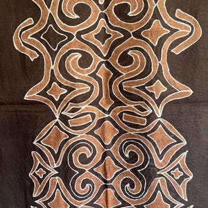 May include: A brown fabric with a white geometric pattern. The pattern is made up of repeating shapes, including diamonds, swirls, and stars.