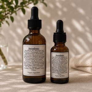 May include: Two amber glass dropper bottles of skincare serum. The bottles have black droppers and white labels with ingredient lists. The larger bottle is approximately 4 inches tall, and the smaller bottle is about 3 inches tall. The text "Organic Ingredients" is visible on the label.
