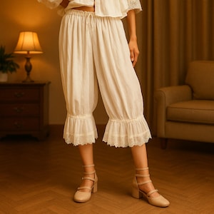 Peut inclure: Pantalon de pyjama court de couleur crème, avec une taille à cordon et des ourlets à volants et garnis de dentelle. Le pantalon fait partie d'un ensemble assorti. L'image montre le pantalon avec un haut et des chaussures assortis.