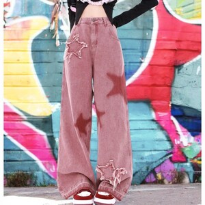 May include: Wide-leg, red-toned denim jeans with distressed details and star-shaped patches.