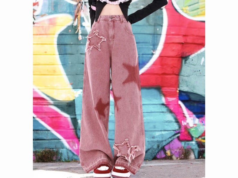 May include: Wide-leg, red-toned denim jeans with distressed details and star-shaped patches.