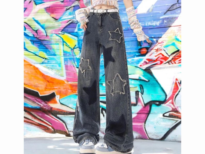 May include: A pair of dark blue denim jeans with large star-shaped patches. The jeans have a wide leg and a high waist.
