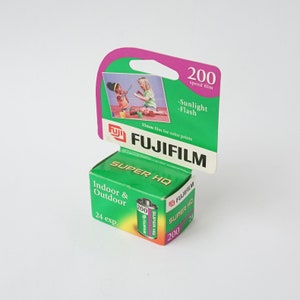 Puede incluir: Una caja verde y rosa de película Fujifilm Super HQ 200 ISO. La caja dice "Interior & Exterior" y "24 exp."