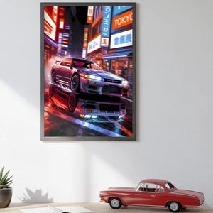 May include: A framed print of a silver sports car driving through a neon-lit city street at night. The car is a Nissan Skyline GT-R R33. The street is lined with Japanese signs and buildings. The print is in a black frame.