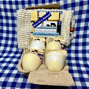 May include: A collection of soaps and a natural fiber washcloth. The soaps are in various shapes and sizes, with a light yellow color. The packaging includes a card with the text "Give fat a chance!" and the website www.FatChanceSoap.com.