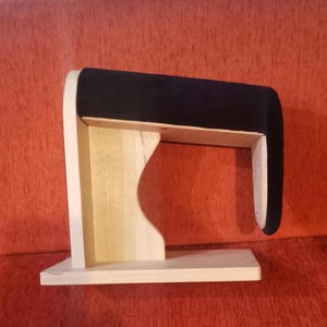 Könnte beinhalten: Eine Armlehne aus Holz mit einer schwarzen gepolsterten Oberseite. Die Armlehne ist für die Verwendung auf einem Sofa oder Sessel konzipiert.