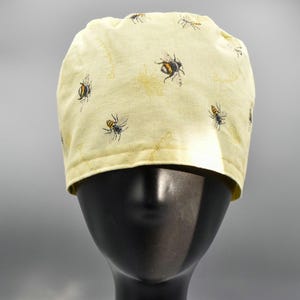 Buzz, Buzz! Bedårande kirurgisk skrubbmössa med humlamotiv och knytband. Ge arbetsdagen lite solsken.