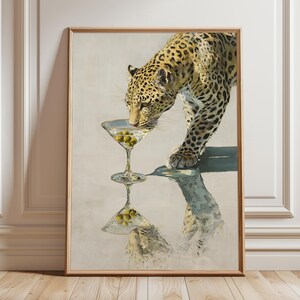 Könnte beinhalten: Gerahmter Kunstdruck mit einem Leoparden, der aus einem Martini-Glas mit Oliven trinkt. Das Fell des Leoparden ist gefleckt, und sein Spiegelbild ist im Wasser zu sehen. Das Kunstwerk hat einen Vintage- und künstlerischen Stil.