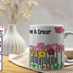 Op de afbeelding: Witte keramische mok met de tekst "ne A Crecer" en een bloemenontwerp. De mok bevat namen als Nicolas, Jesus en Emma. Een cartoonvlinder en bloemen versieren de mok.